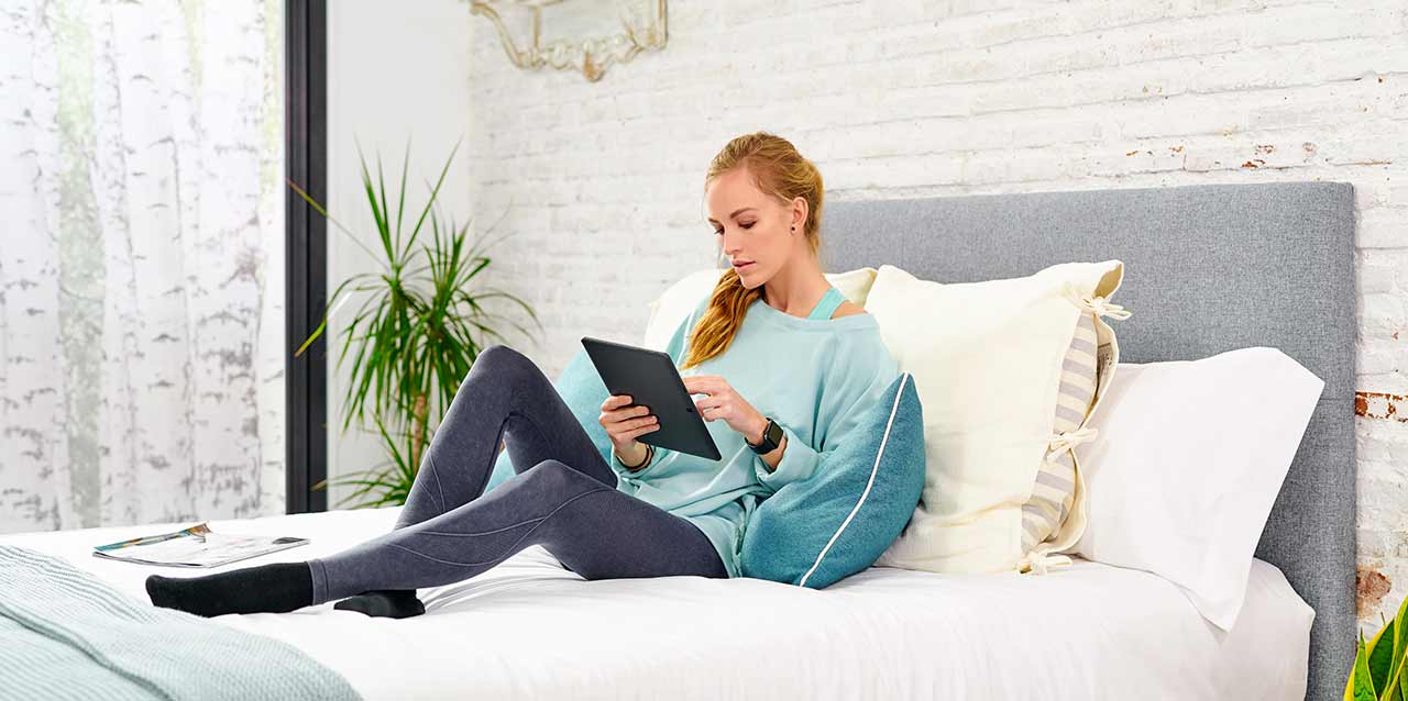 mujer sentada en colchón con tablet