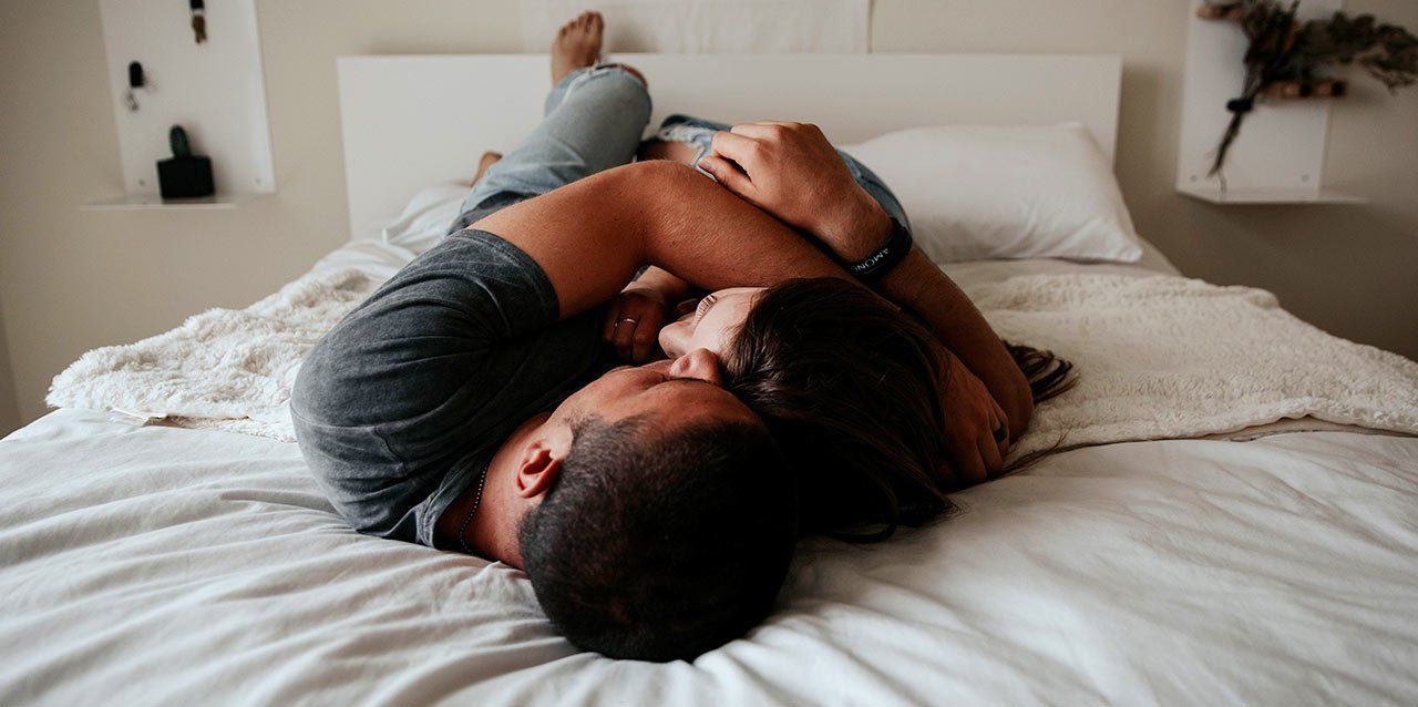 pareja abrazada tumbada en colchóon con nórdico