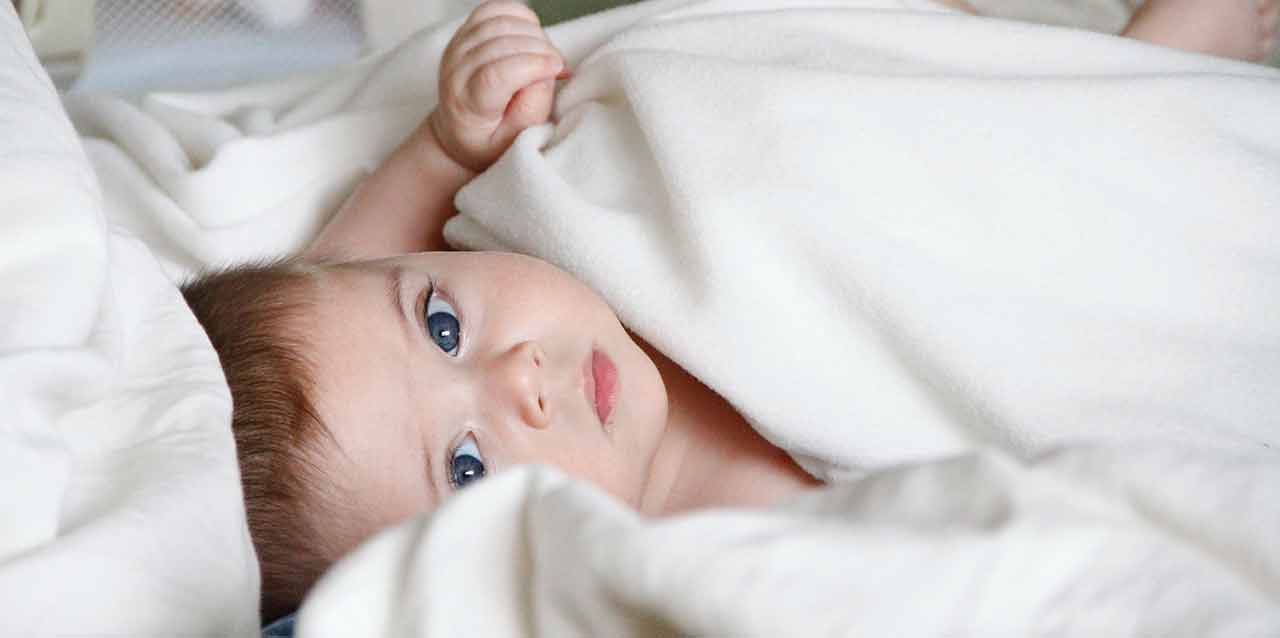 bebé de ojos azules tapado en cuna