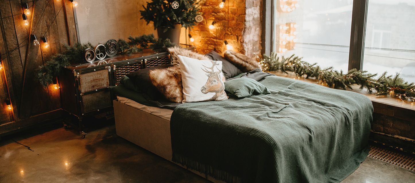 cama con sabanas de franela, 8 cojines, cabecero rustico en una habitación con decoracion navideña