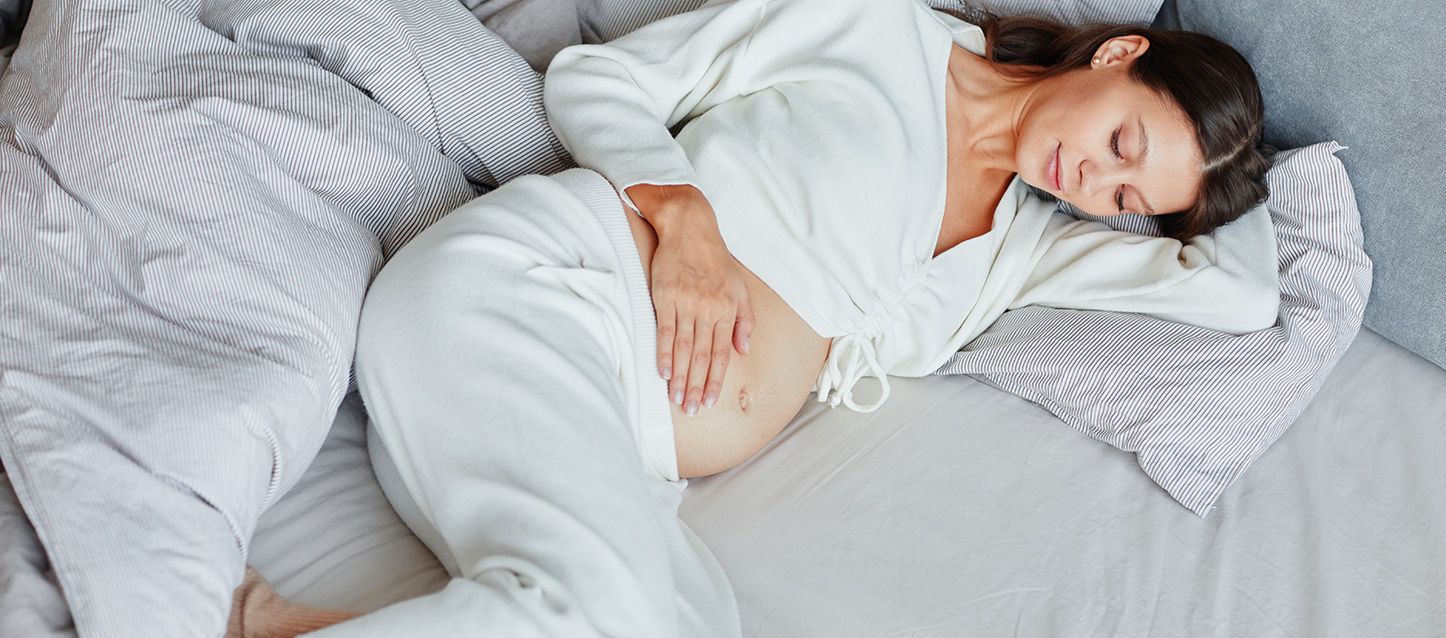 mujer embarazada descansando en la cama boca arriba y de lado mirando su barriga
